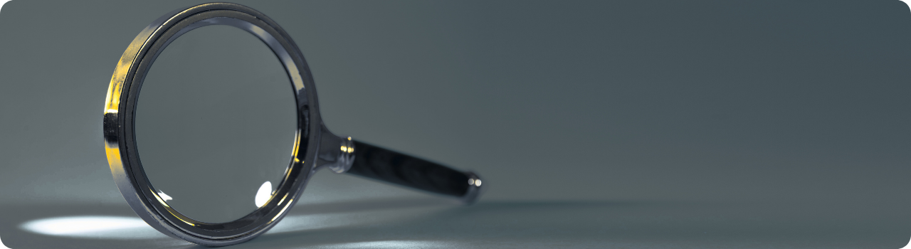 Magnifying glass on a grey surface, representing constituent-level analysis of US leveraged and inverse ETF holdings