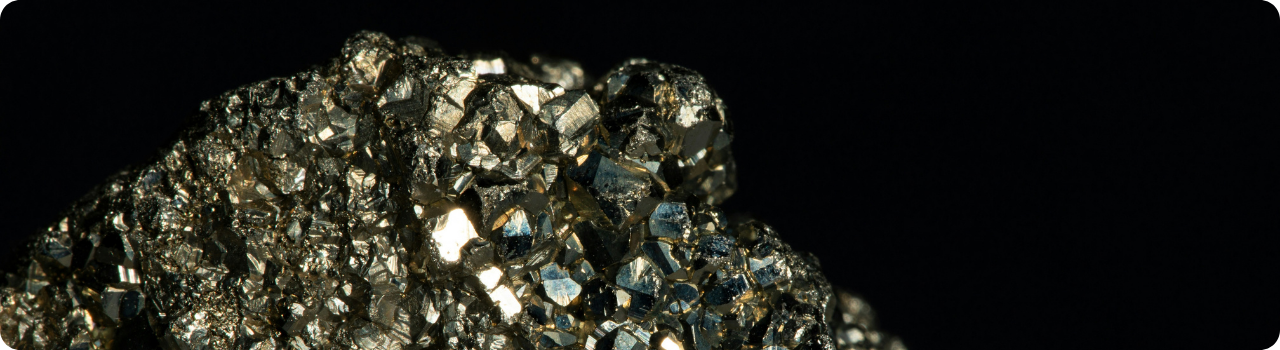 Close-up of a rough metallic mineral specimen against black, used to illustrate rare earth supply chains.