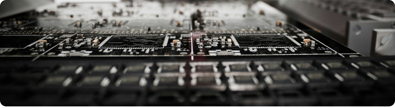 Close-up of a printed circuit board with surface-mounted components, shot in shallow focus under low light.